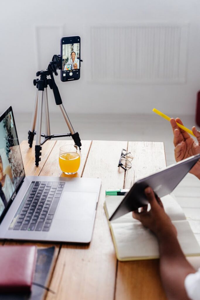 A person using a digital tablet and smartphone with tripod for a virtual meeting.