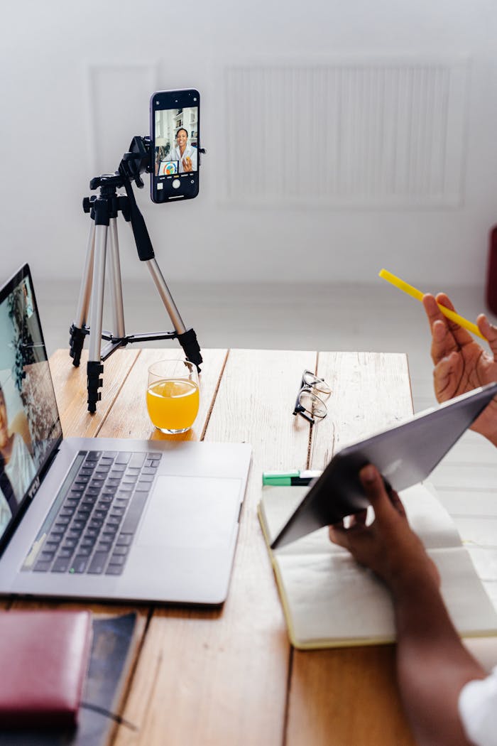 A person using a digital tablet and smartphone with tripod for a virtual meeting.